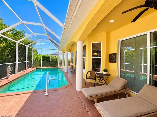 Screen-enclosed swimming pool featuring a tiled deck, covered patio, structural columns, and recessed lighting