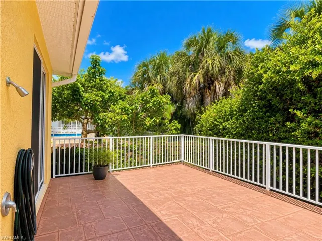 Outdoor patio featuring stamped concrete flooring, white metal railing, and wall-mounted exterior fixtures