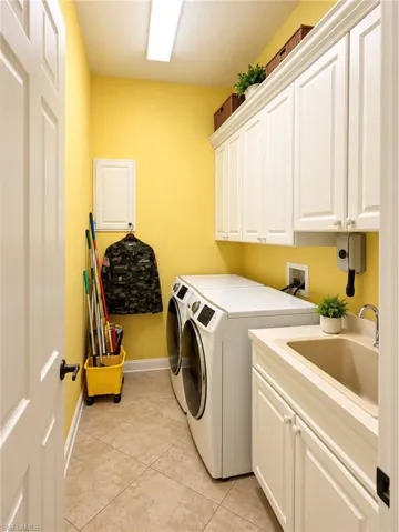 Utility room featuring extensive white shaker-style cabinetry, a drop-in basin sink, tile flooring, and integrated laundry hookups