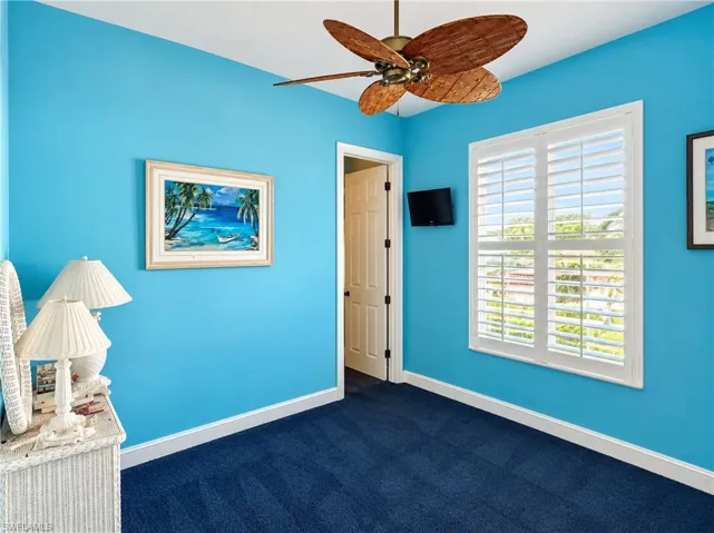 Room featuring plantation shutters, a multi-blade ceiling fan with a wood-tone finish, and wall-to-wall carpeting