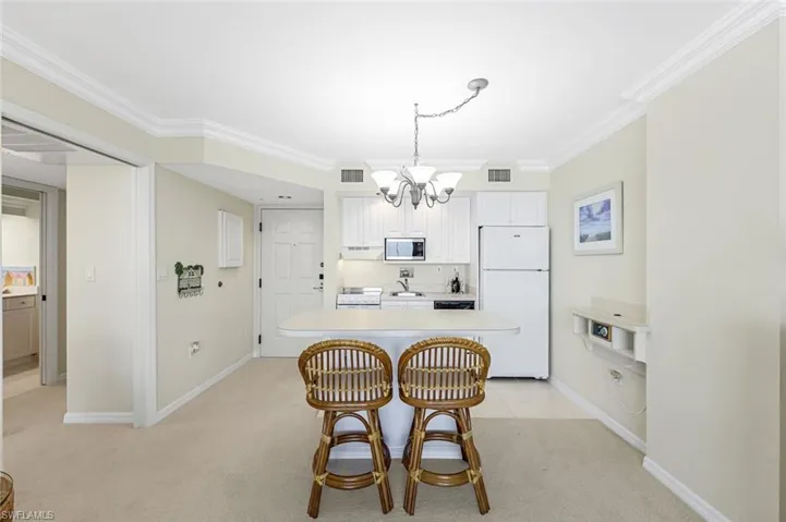 Dining area featuring a chandelier, baseboards, ornamental molding, and light carpet
