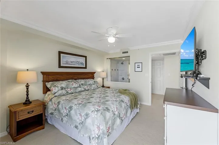 Bedroom with light colored carpet, crown molding, baseboards, and a ceiling fan