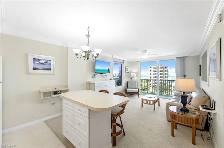 Kitchen with crown molding, light countertops, a breakfast bar area, white cabinets, and a center island
