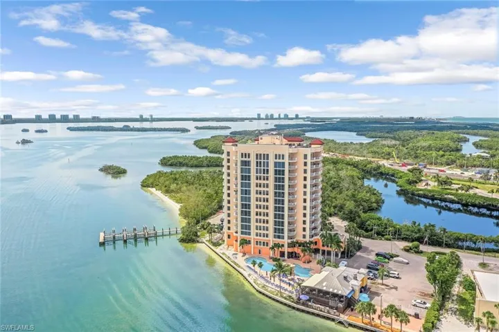 Aerial view of a nearby body of water, apartment complex, and a pool