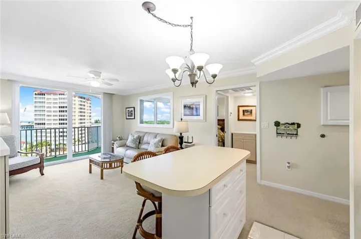 Kitchen with light carpet, light countertops, a chandelier, open floor plan, and a kitchen island