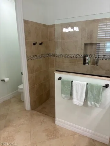 Bathroom featuring tiled shower and toilet