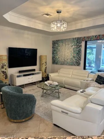 Living room featuring ornamental molding, a notable chandelier, and light tile patterned floors