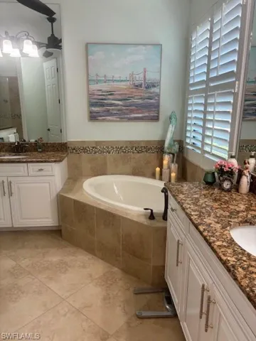 Bathroom featuring a relaxing tiled tub, tile patterned flooring, plenty of natural light, and vanity