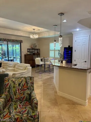 Living room featuring a notable chandelier, light tile patterned floors, and ornamental molding