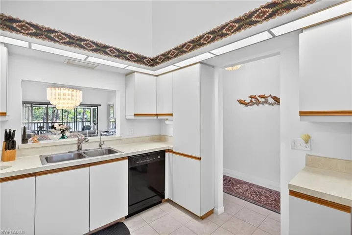 Kitchen with light countertops, a chandelier,  light tile patterned floors, and two tone cabinets