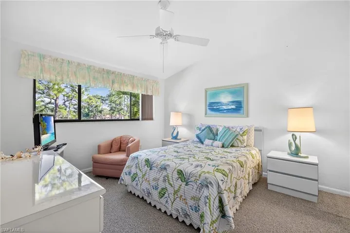 Primary bedroom overlooking lake with lofted ceiling and a ceiling fan