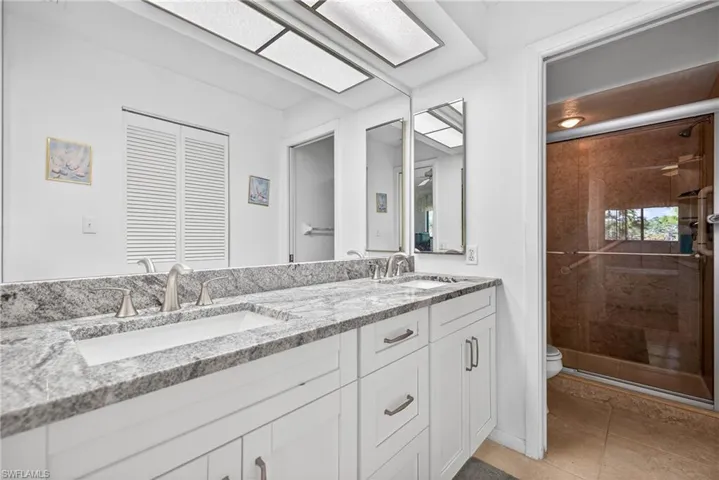 Bathroom with double vanity, walk in shower, and light tile patterned floors