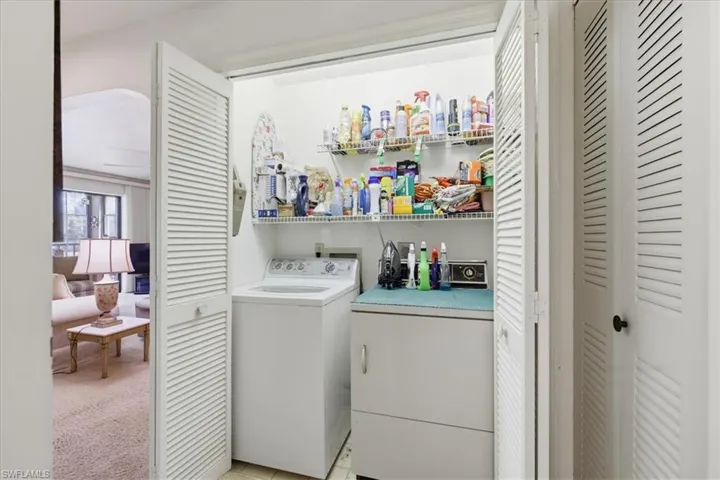 Laundry area with washing machine and dryer and light colored carpet
