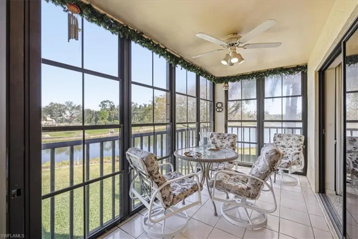 Sunroom / solarium with tile patterned flooring and a water view