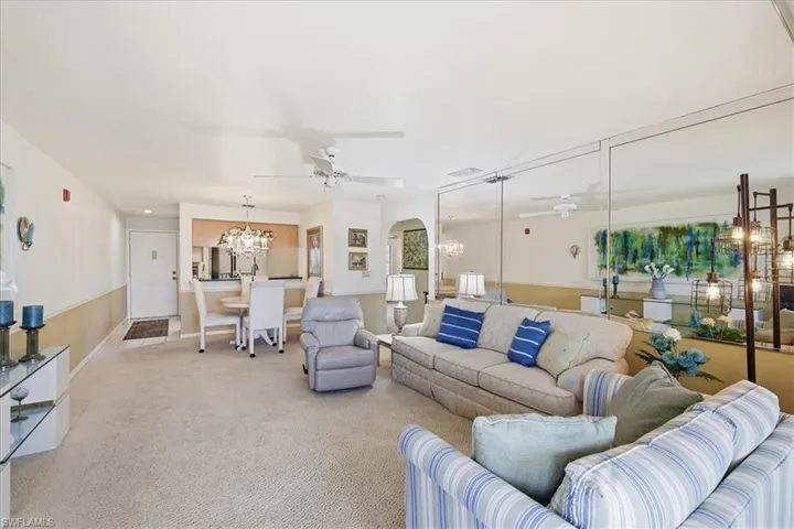 Carpeted living room with a chandelier, a ceiling fan, and arched walkways