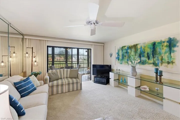 Living area featuring light colored carpet and a ceiling fan