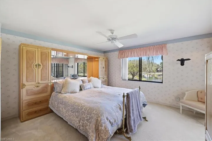 Bedroom featuring wallpapered walls, light colored carpet, and ceiling fan