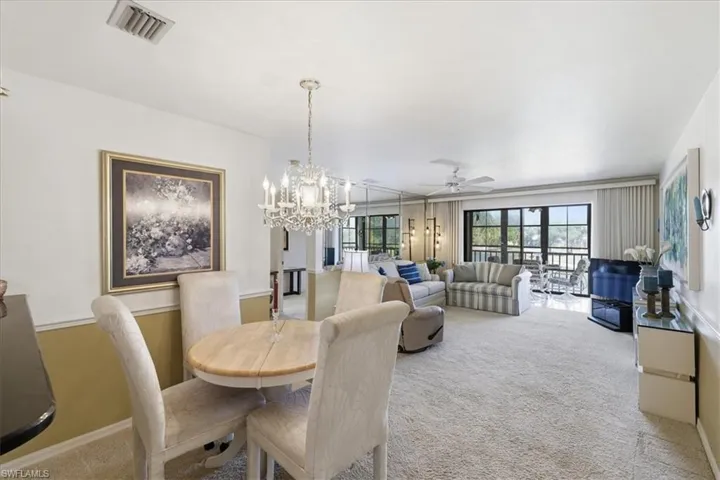 Dining space featuring a ceiling fan, hanging lights, and carpet