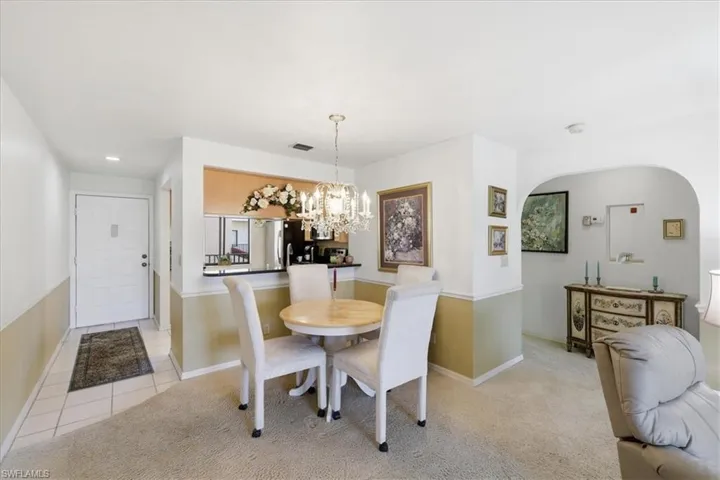 Dining room with light carpet, hanging lights, and light tile patterned floors