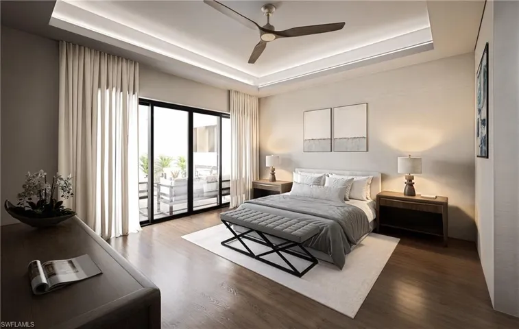Bedroom with a tray ceiling, wood finished floors, access to outside, and a ceiling fan