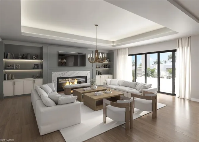 Living room with a premium fireplace, wood finished floors, a chandelier, a tray ceiling, and built in shelves