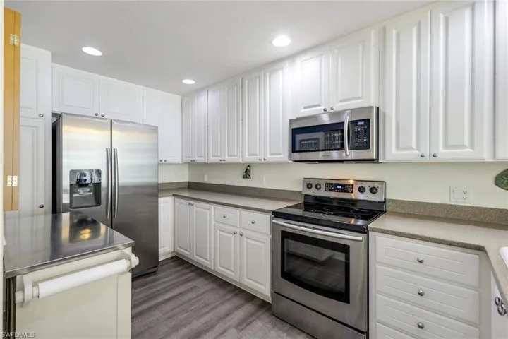 Kitchen featuring White Cabinets, Corian Countertops, Samsung- Stainless Steel Appliances & Portable Island