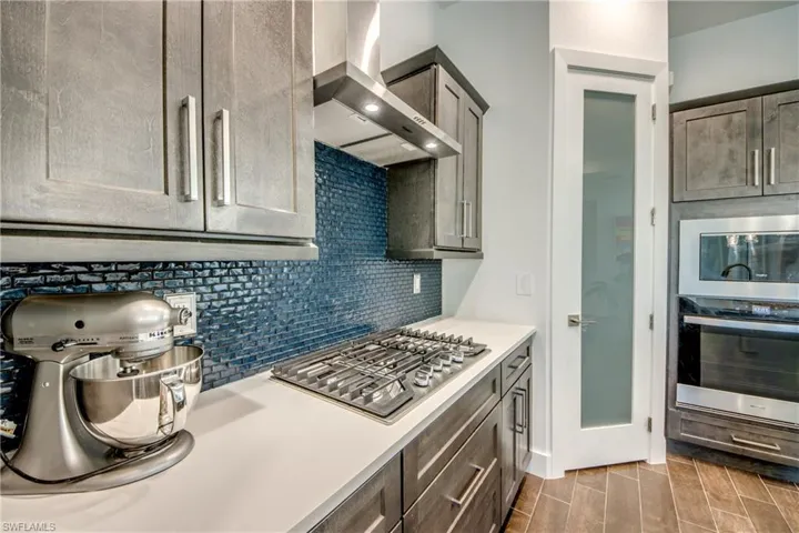 Kitchen with stainless steel appliances, wood finish floors, and decorative backsplash
