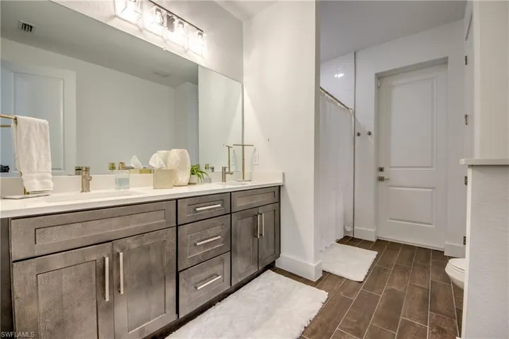 Full bathroom with double vanity, a stall shower, and wood finish floors