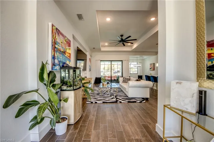 Living area featuring wood tiled floors, recessed lighting, ceiling fan, and a tray ceiling