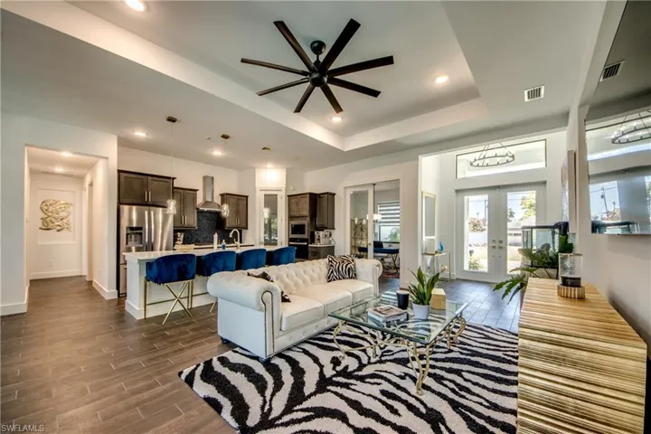 Living room featuring a ceiling fan, wood tiled floors, french doors, recessed lighting, and a tray ceiling