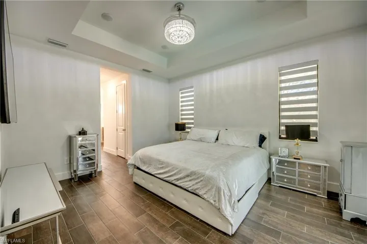 Bedroom featuring wood finish floors, a tray ceiling, and a chandelier