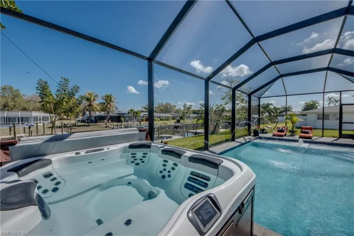 View of pool featuring a hot tub, a lanai, a sunroom, and a water view