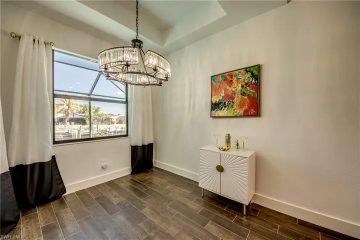Dining room featuring wood finish floors, suspended lighting, and a raised ceiling