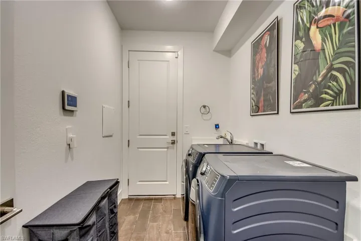Laundry area featuring wood finish floors, separate washer and dryer, and a textured wall