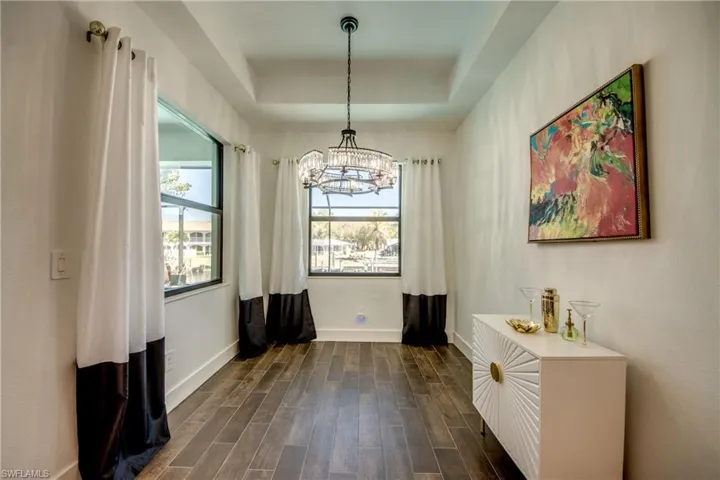 Dining room with a tray ceiling, wood tiled floors, and a chandelier
