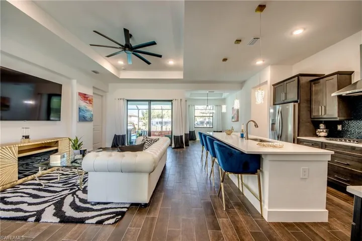 Living area with ceiling fan, wood tiled floors, a tray ceiling, and a chandelier