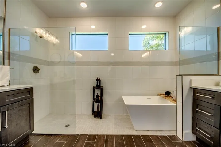Bathroom featuring vanity, tile walls, a soaking tub, a walk in shower, and plenty of natural light