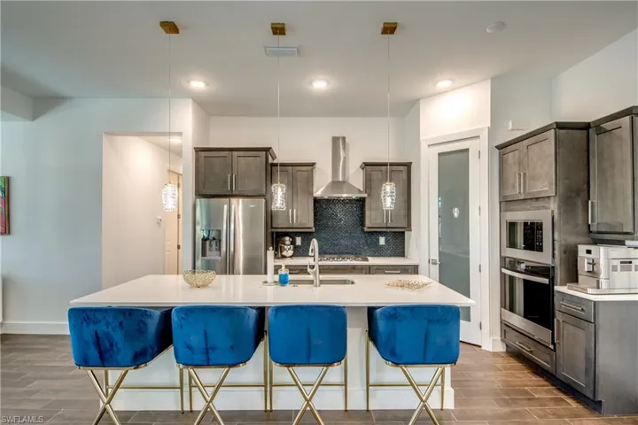 Kitchen with dark wood finish cabinetry, a kitchen breakfast bar, stainless steel appliances, an island with sink, and wood tiled floors