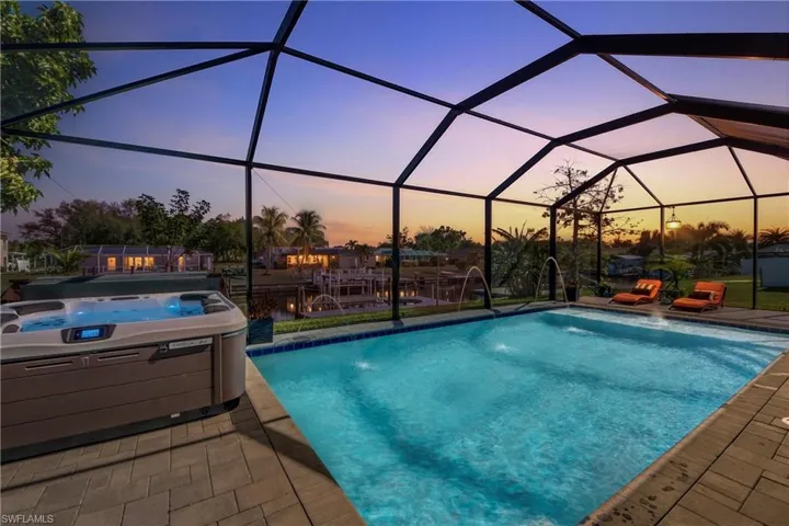 Outdoor pool with a hot tub, a sunroom, glass enclosure, and a patio area