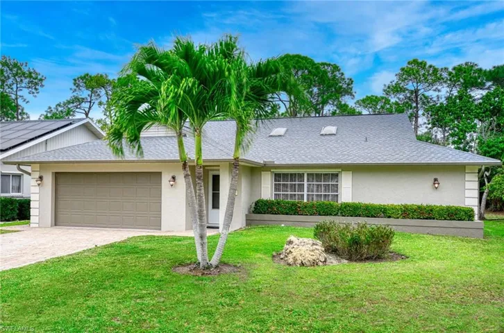 Ranch-style house with roof with shingles, a garage, driveway, a front lawn, and stucco siding