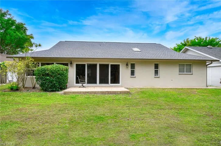 Rear view of property with roof with shingles, a yard, stucco siding, and a sunroom