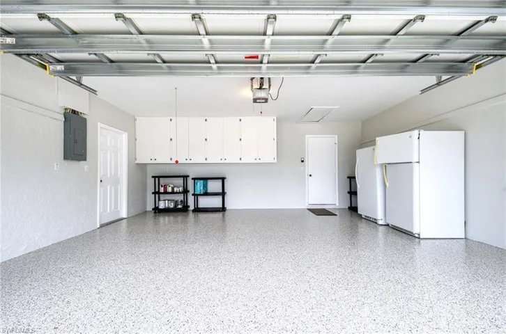 Garage featuring freestanding refrigerator and electric panel