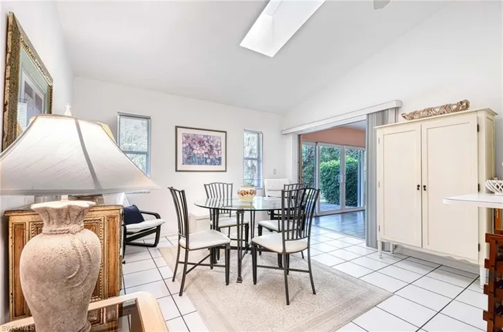 Dining area with a skylight, light tile patterned flooring, and vaulted ceiling