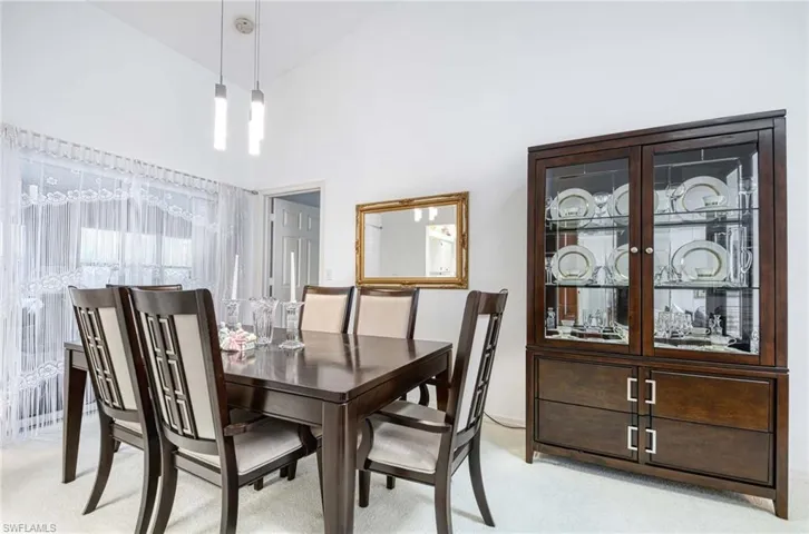 Dining area with light carpet and a high ceiling