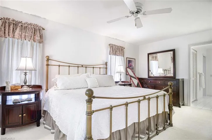 Bedroom with light colored carpet, a ceiling fan, and multiple windows