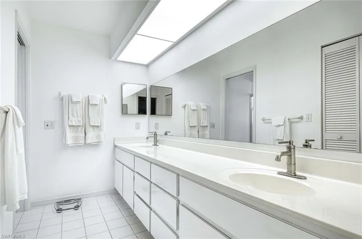 Full bath with double vanity, light tile patterned flooring, and a closet