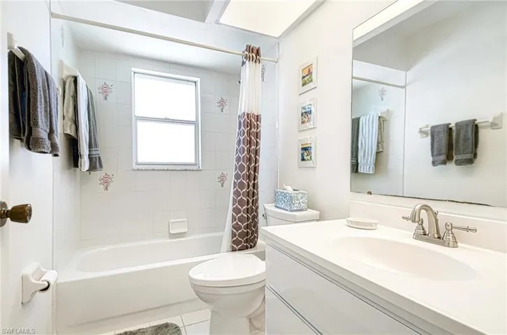 Full bathroom with vanity, shower / bath combination with curtain, and light tile patterned floors