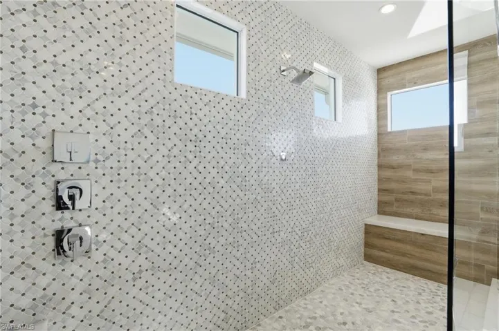 Oversized shower w/ designer tile finishes, multiple shower heads not pictured to include rain shower head, handheld, fixed.