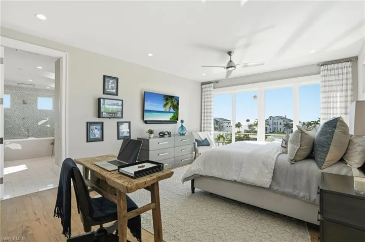 Primary ensuite, walk-in closet with built-ins, oak hardwood floor, impact slider, balcony with gulf views.