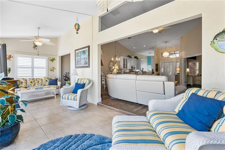 Living room featuring ceiling fan, tile patterned floors, and high vaulted ceiling